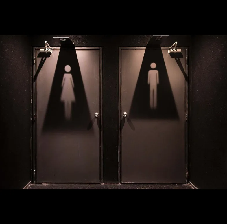 Puertas de los sanitarios con la señalética proyectada con luz